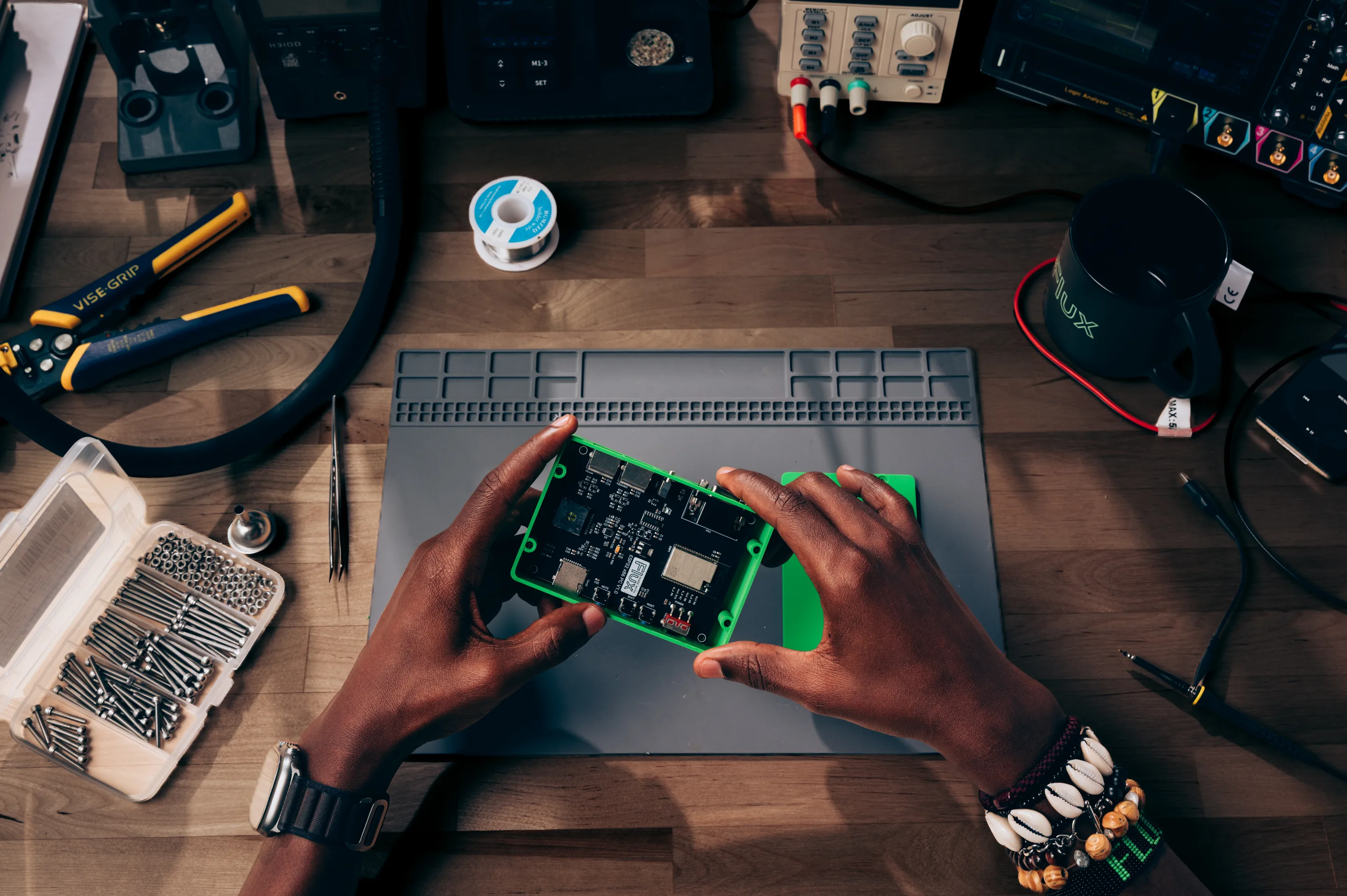 Hands fitting a circuit board into a green 3D-printed enclosure on a workbench